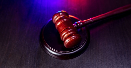Judge's gavel on wooden table with strobe lights in the background